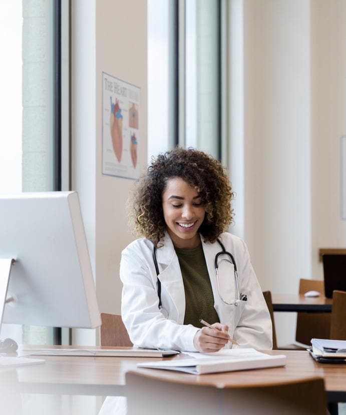 Smiling doctor writing notes during a follow-up consultation after an abortion.
