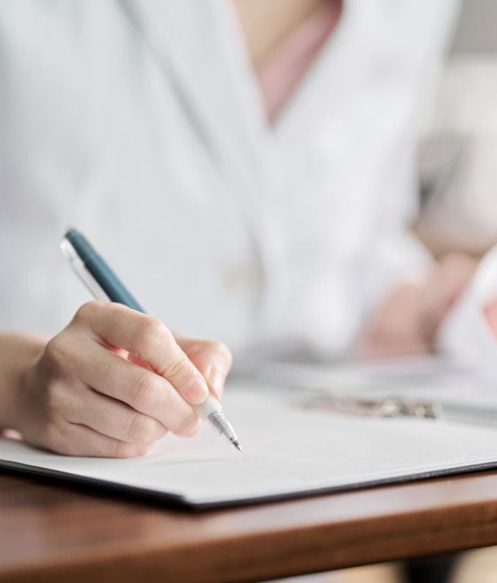 Doctor writing notes during a follow-up consultation after an abortion.